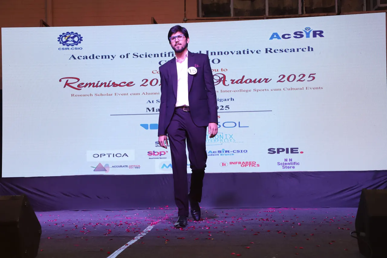 A participant in a dark suit walks towards the audience on the ramp