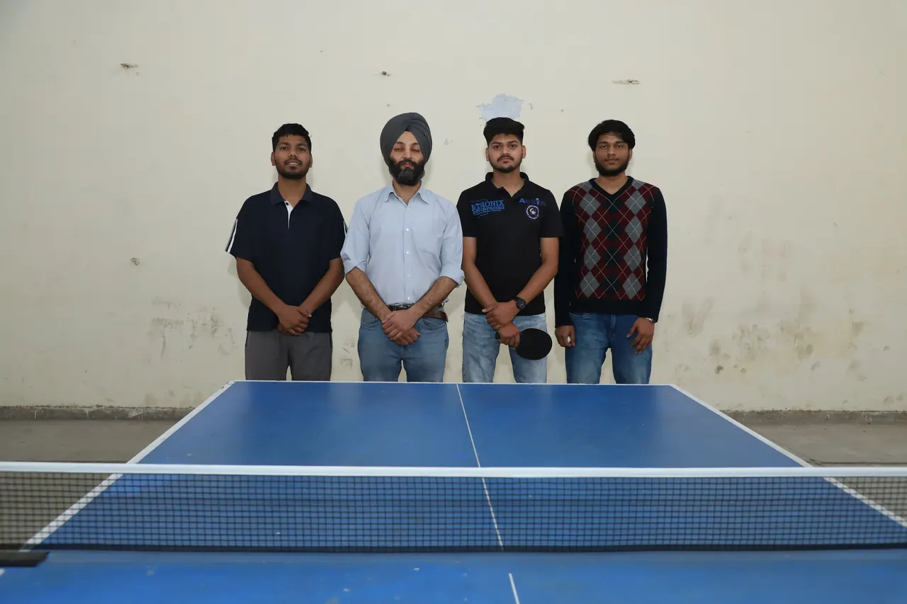 Four table tennis players stand together behind the table before play