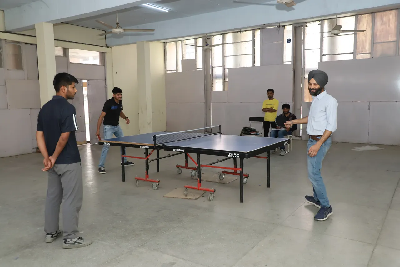 A table tennis match in the indoor hall with a match official watching